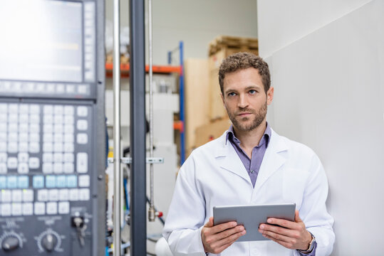 Employee checking manufacturing machines in high tech company, using digital tablet