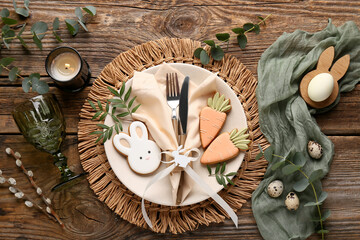 Beautiful table setting with different Easter cookies, eggs, burning candle and eucalyptus branches on wooden background © Pixel-Shot