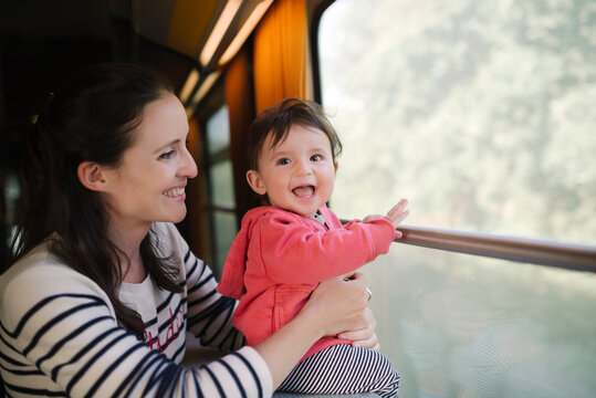 Happy mother and baby girl traveling by train