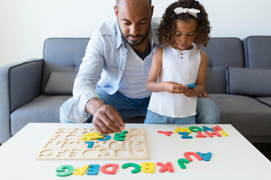 Father and daughter playing with alphabet learning game at home