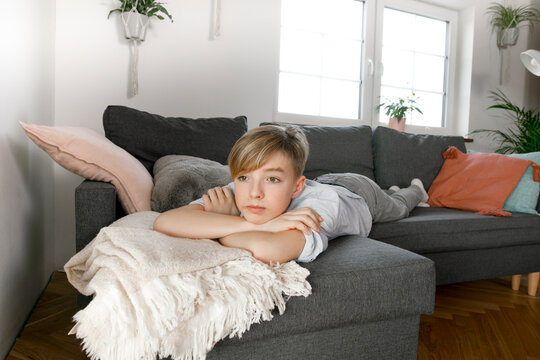 Teenage boy lying on couch, looking bored