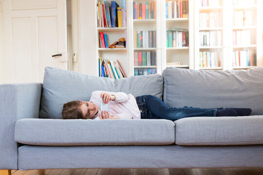 Girl lying on couch at home holding cell phone