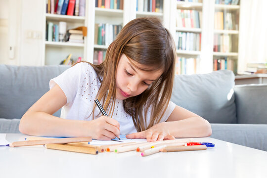 Portrait of girl drawing with coloured pencil at home