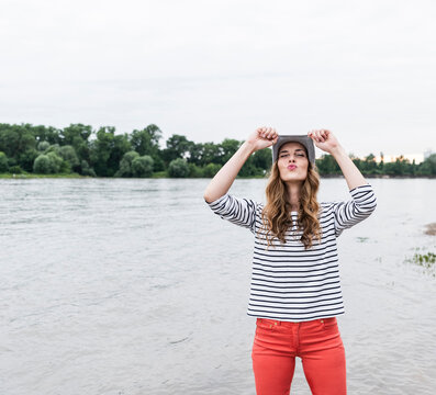 Playful woman wearing wooly hat at a river pouting