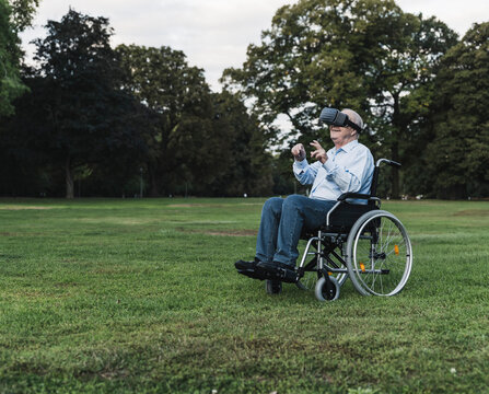 Senior man sitting in wheelchair in a park using Virtual Reality Glasses