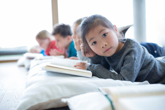 Schoolgirl takes a break with friends, reading on the floor in the school break room