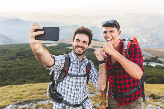 Italy, Monte Nerone, two happy hikers on top of a mountain taking a selfie