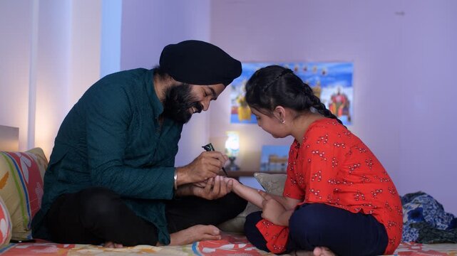 A North Indian Sardar wearing a turban is putting Mehendi on his daughter's hand - Henna  festival time  girl hobby. A middle-aged guy and a little kid together in the bedroom - parent-child bondin...