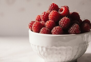 Fresh raspberries piled high in a white bowl, bathed in soft natural light