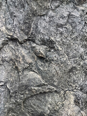 Dark rough rock texture with natural stone patterns and gritty surface details for backgrounds	