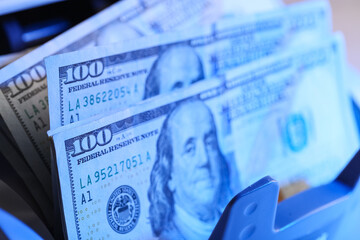 Fototapeta premium Modern cash counting machine scanning ultraviolet with dollar banknotes, closeup