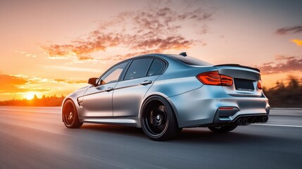 Fototapeta premium Silver sedan speeding down highway at sunset with dramatic clouds and warm sky