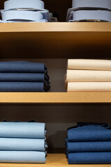 Male perfectionism is expressed in clothes folded on closet shelf. Neatly arranged classic pieces represent man who appreciates order. Folded clothes in wardrobe symbolize desire for perfect clothes