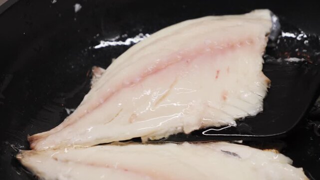 Preparing fresh fish fillet in a hot pan with oil to make a delicious meal, close-up of white fish fillet. High quality 4k footage