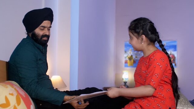 A handsome Punjabi Sardar father checking his girl kid school report card and signing it - single father. An Indian father with his daughter - signing exam paper report  happy parent  hardworking  ...