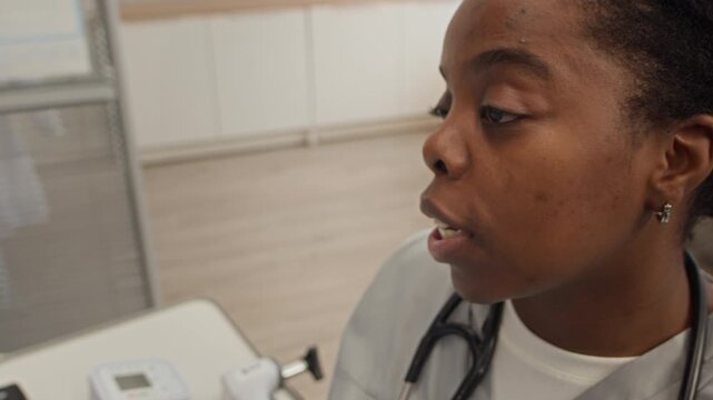 Closeup of African American female medical professional starting cervical gland and lymph node palpation exam as part of comprehensive patient checkup