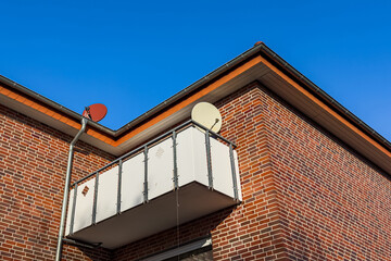 Obraz premium Balcony with satellite dishes on a brick building in clear weather