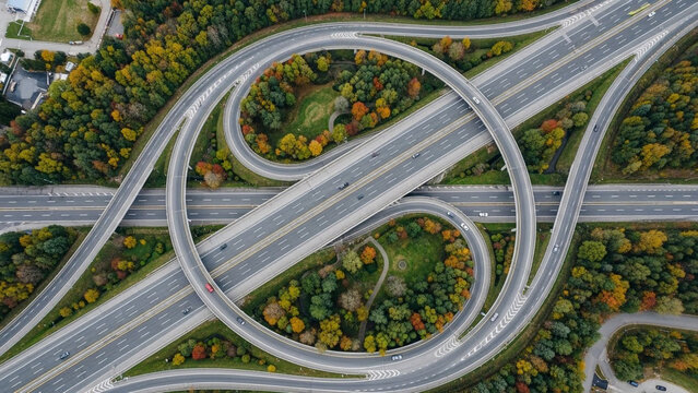 Aerial Top Down View of Complex Highway Interchange and Multi-Level Road Junction Surrounded by Colorful Autumn Forest