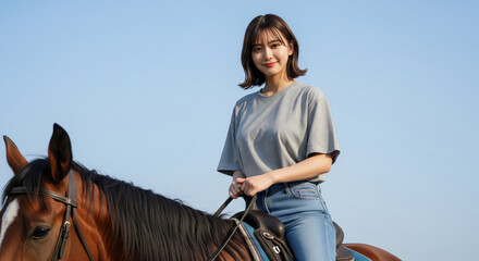 青空の下で茶色の馬に跨り穏やかな表情を浮かべて佇む女性