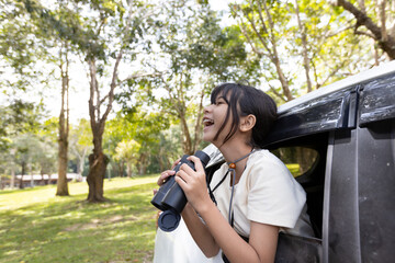 Young Girl Holding Binoculars Leaning Out of Car in Nature