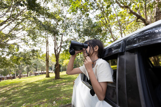 Young Girl Birdwatching with Binoculars from Car in Nature