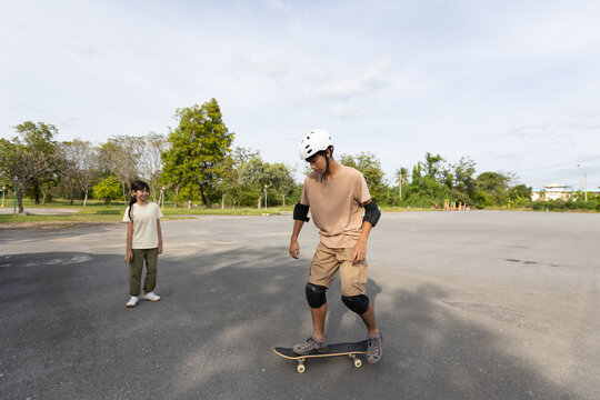 Teenage Asian Boy Practicing Skateboarding in Park with Protective Gear