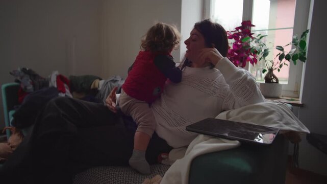 Mother lifting toddler from lap after screen use expressing reconnection presence caregiving warmth emotional shift from distraction to bonding at home