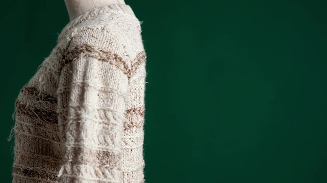 Medium shot of lowimpact textured knitwear emphasizing innovative compostable fibers and intricate patterns in a green studio setting.