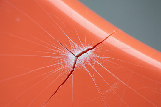 Close up of cracked orange plastic surface texture representing material damage, fragility and impact accident for construction background or quality control concept