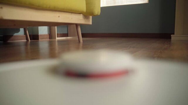 Robot vacuum cleaner gliding across a shiny wooden floor in a modern living room, showcasing autonomous smart home cleaning technology, efficiency and effortless daily maintenance