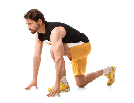 Sporty young man in crouch start position for marathon on white background