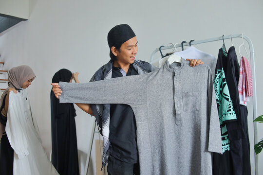 Young Muslim Male Showing Grey Koko Shirt While Family Shops For Eid Lebaran Clothes In Background