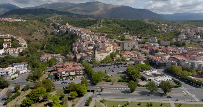 Aerial view of a historic town nestled against a lush hillside. Panorama of Scalea, a town in the province of Cosenza, in Calabria, Southern Italy. The Calabrian Apennines are in the background.