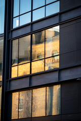 Reflections of old buildings in a new glass building, London, England, UK