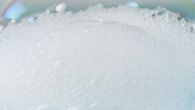 Close-up shot of iridescent soap bubbles rising and dissipating in foamy water, symbolizing purity, joy, renewal, and ephemeral moments
