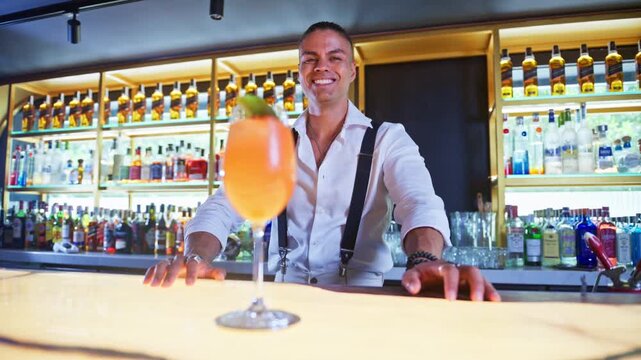 Professional bartender serving an aperol spritz cocktail at bar