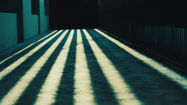 Sunbeams casting long, parallel shadows across a textured concrete surface, forming a graphic pattern with strong contrast between light and dark areas through an alleyway