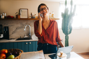 Fototapeta premium Woman on phone in cozy kitchen with laptop
