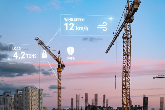 Smart construction site with real-time data monitoring wind speed and load on tower cranes against a beautiful sunset sky, showcasing safety and efficiency in modern building development.