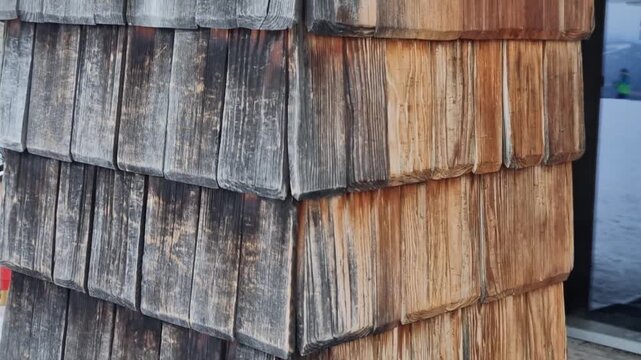 wooden shingles, wall cladding, made from cedar or larch.  older weathered, with gray patina. historical building church, chapel, castle, chateaux traditional cottage. Facade cladding of mountain hut