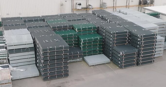 Stacked metal fence panels at an outdoor industrial storage yard