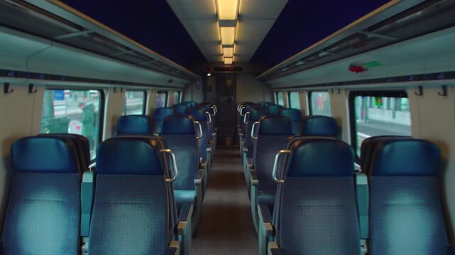 Walking forward through empty commuter train aisle before departure with repeating seats symmetry depth and quiet motion evoking anticipation routine travel and transitional urban calm