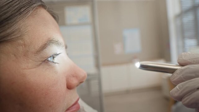 Closeup of female patient receiving eye examination from gloved doctor in modern clinic using professional equipment and medical tools for vision and eye health assessment