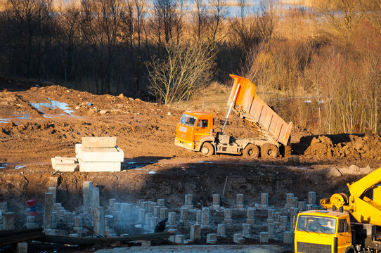 Construction site working, view from height of a tip truck unloading clods of soil during construction works, panel houses construction in process