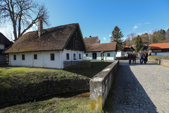 View of rustic, whitewashed houses with thatched roofs stand as silent witnesses along a cobblestone path under a clear sky, Kumrovec, Krapina-Zagorje County, Croatia.
