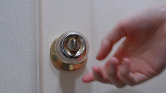 A woman's hand compulsively touches and turns the doorknob, showing symptoms of obsessive-compulsive disorder with repetitive behaviors, opening and closing the door to the room.