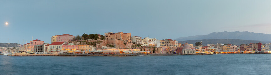 Fototapeta premium Pastel evening light over colorful historic waterfront buildings and harbor promenade in Chania old town, Crete island, Greece