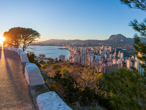 View of golden sunlight kissing the cityscape as it rises over the coast, illuminating the buildings in a warm glow, Benidorm, Valencian Community, Spain.