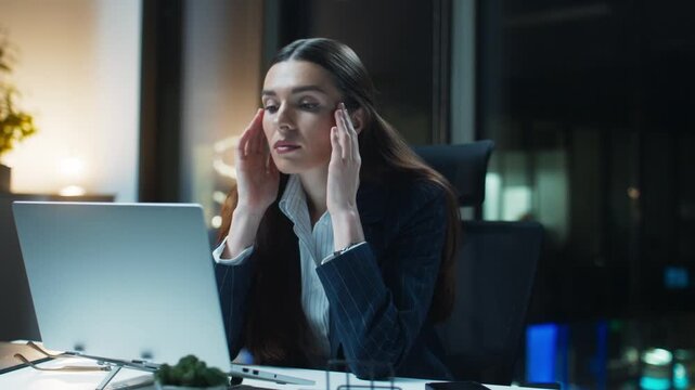 Office fatigue scene with Caucasian woman sitting at desk. Female professional holding head and closing eyes. Young employee experiencing headache while working. Laptop screen in front.