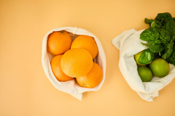 Colorful fruits and herbs are arranged in reusable cloth bags on a pastel background, highlighting the importance of eco-friendly grocery shopping and healthy eating habits.
